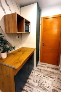 Entrada de la habitación con mesa auxiliar de madera y puerta de acceso