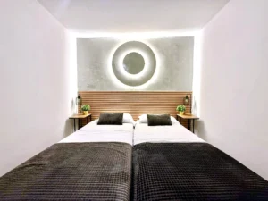 Dormitorio moderno con iluminación circular en la pared y camas gemelas
