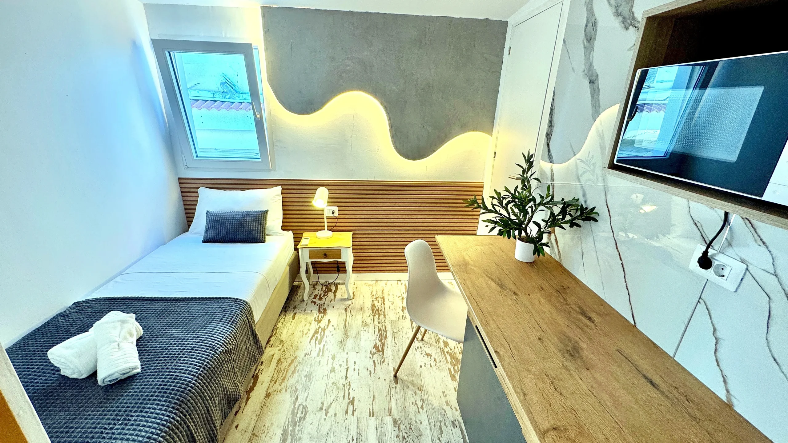 Habitación individual privada con escritorio de trabajo, televisión y cama sencilla