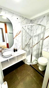 Baño privado con paredes estilo mármol y cabina de ducha de cristal