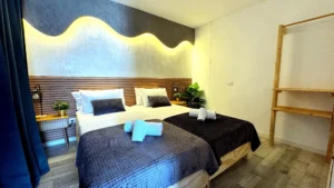 Dormitorio en planta elevada con iluminación LED ambiental y perchero de madera