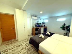 Vista general del dormitorio amplio con suelo de madera y zona de trabajo